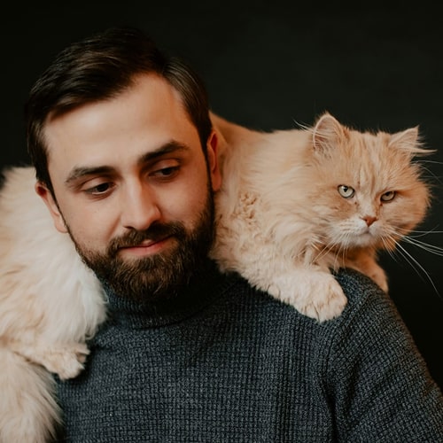 Man and his pet cat lying on his shoulder